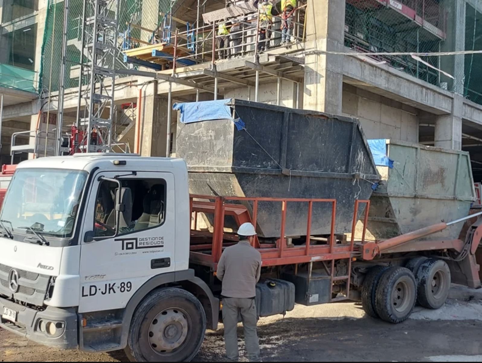 Camión TOL retirando contenedor en obra de construcción
